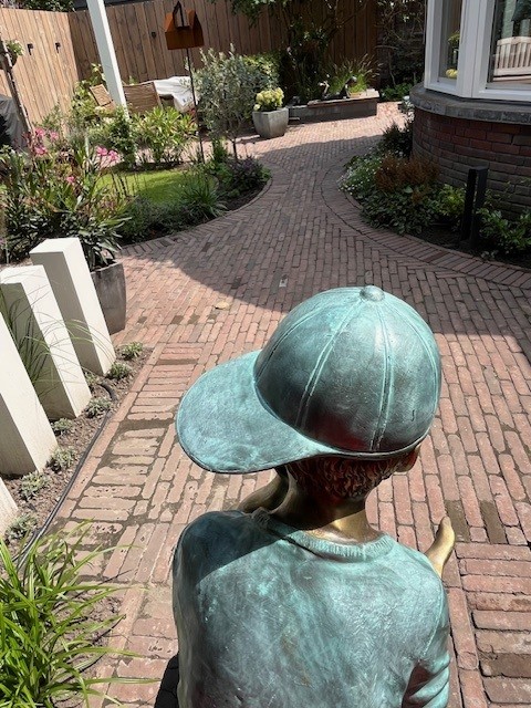 Beeld brons zittende jongen met pet