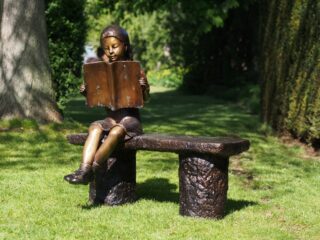 bronze reading girl on bench - eliassen.nl